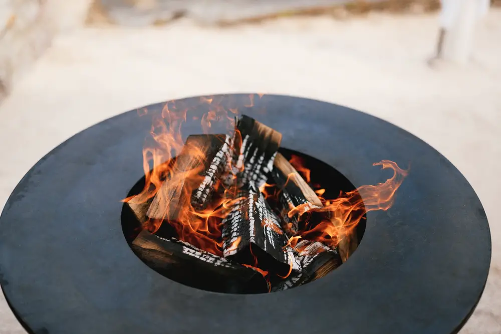 A close-up of the round frying surface with burning wood inside.