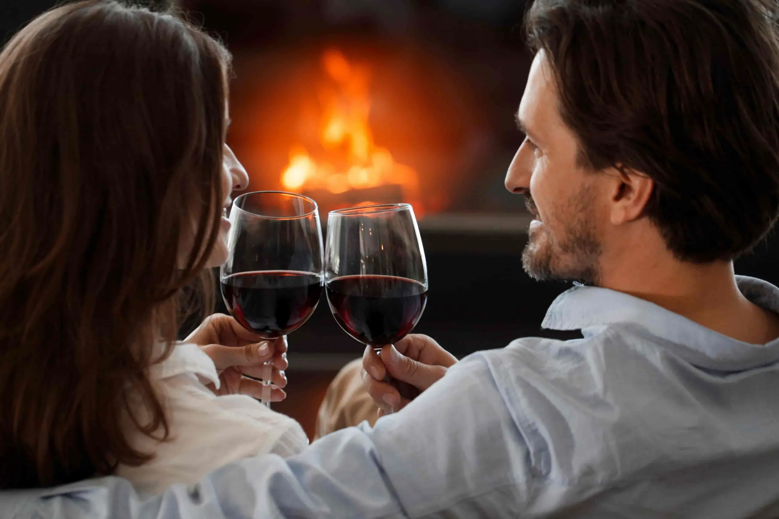 couple drinking wine in front of fireplace
