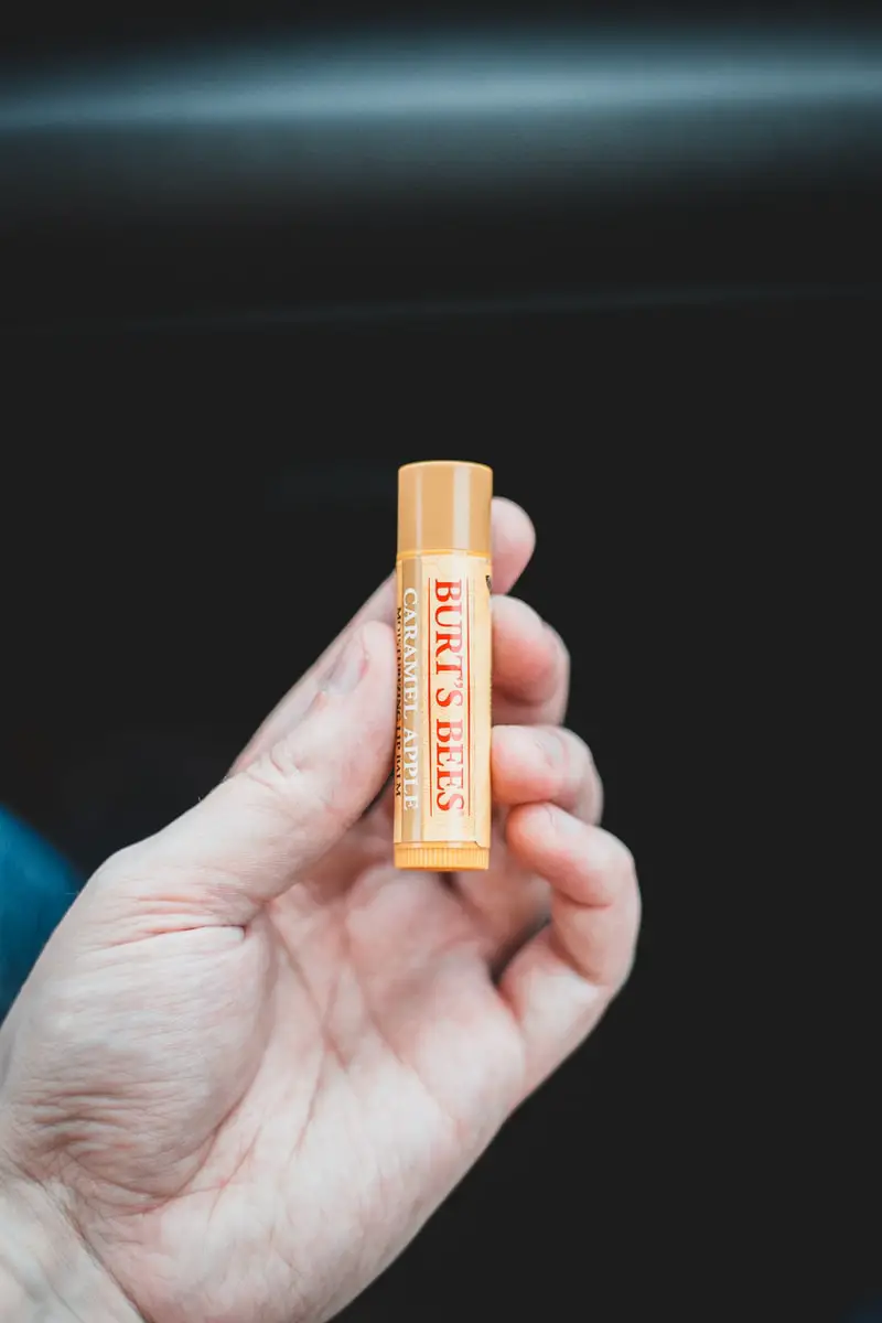 person holding orange and yellow plastic chapstick