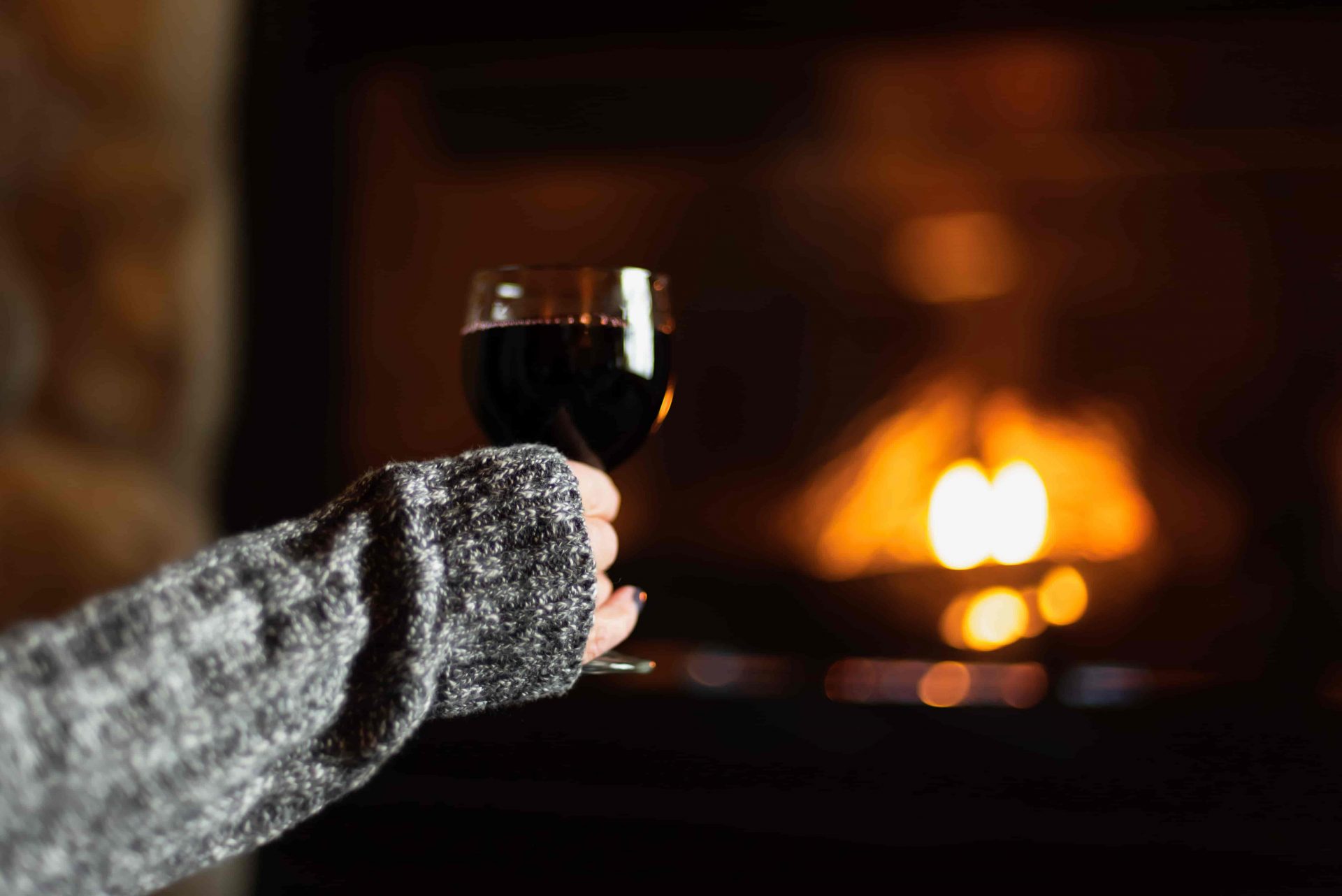 Infrared vs. Electric Fireplaces: DIfferences + Pros & Cons woman drinking wine in front of fireplace