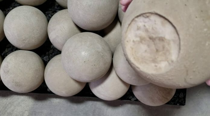 Fireplace Balls: Everything You Need To Know A person is putting clay balls on a tray.