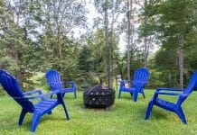 How To Make a Fire Pit Wind Guard Four blue adirondack chairs around a fire pit.
