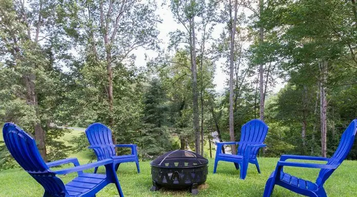 How To Make a Fire Pit Wind Guard Four blue adirondack chairs around a fire pit.