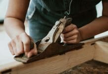 How To Make a Wood Stove Cover A woman is using a sander on a piece of wood.