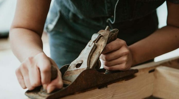 How To Make a Wood Stove Cover A woman is using a sander on a piece of wood.